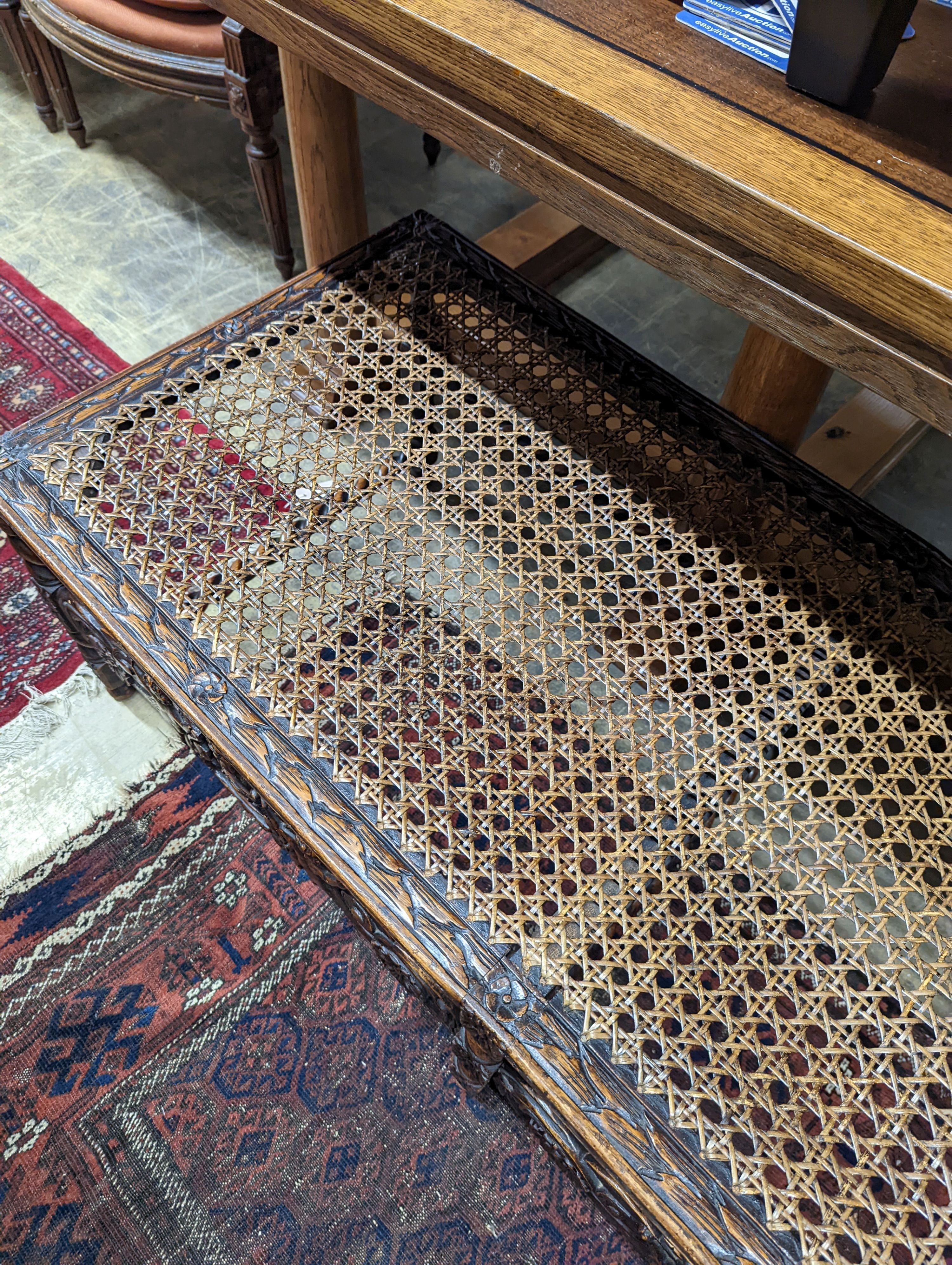 A 1920's Carolean style oak and cane work window seat, length 130cm, depth 58cm, height 44cm